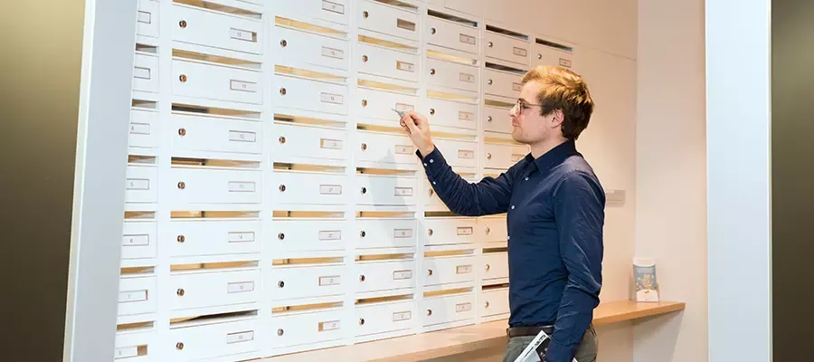 Homme devant des boites aux lettres d'entreprises domiciliées