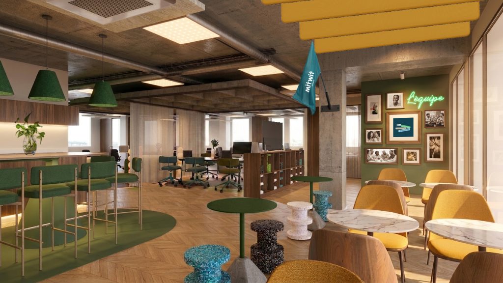 Maquette 3D. Espace commun avec sur la gauche une partie de l'ilot central de la cuisine et les mange debout en guise d'assise. Sur la droite la section restauration avec tables et chaises, et au fond de la pièce se trouvent les postes de coworking.